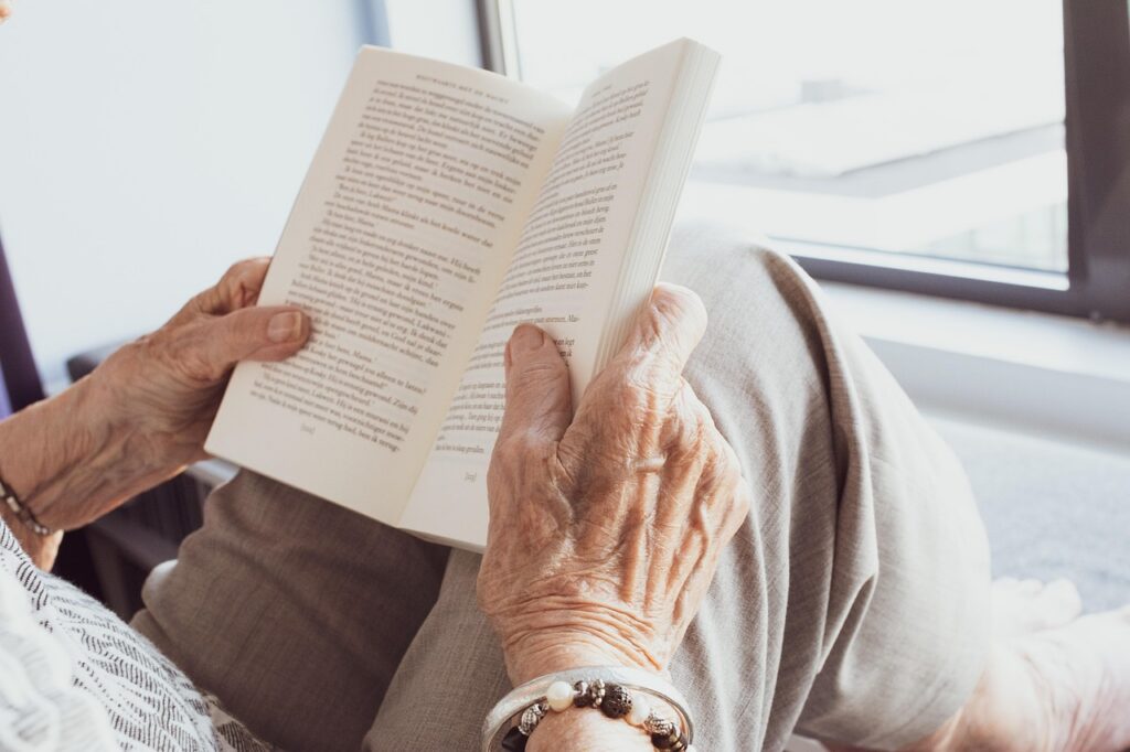 older adults hands holding open book