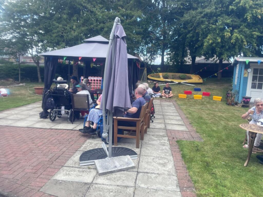 families talking in a garden with a bench